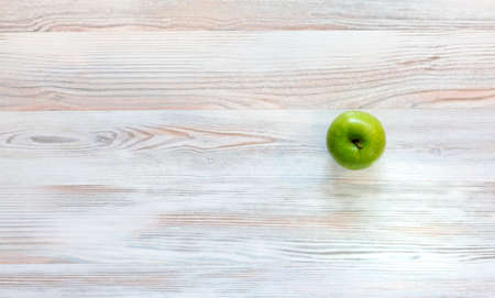 Green apple on wood background Bright green apple located on well-textured birch kind of woodの写真素材