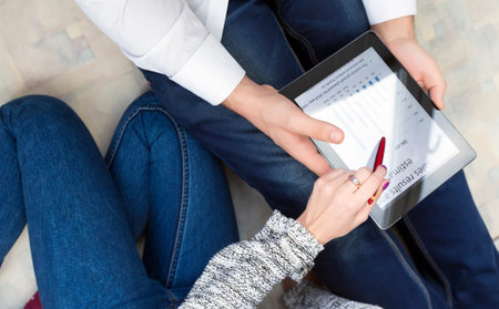 Body of woman and man dressed jeans style sitting relaxing posture and discussing chart on tablet PC...