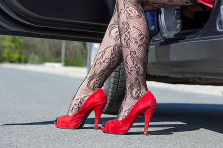 Female leg dressed provocative clubbing pantyhose high heels red shoes step out of the blue carの写真素材