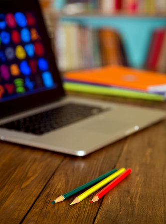 Working place at home Handcrafted natural wooden desk laptop with many blurred colorful icons pencils booklets paperwork angle view home interiorの写真素材