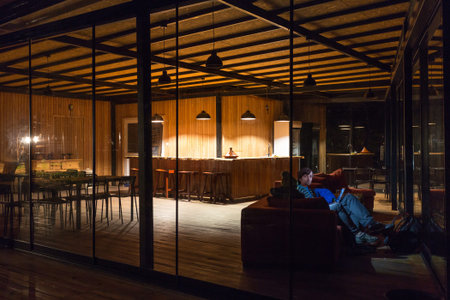 Empty Hotel Reception Desk at Night and People sitting at sofa working on Laptop faces illuminated...