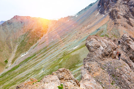 Female mountain climber traversing bright orange red rock moving towards point of shoot color...