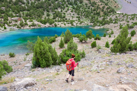 Person Sporty Clothing and Gear Descending to Amazing colored Mountain Lakeの写真素材