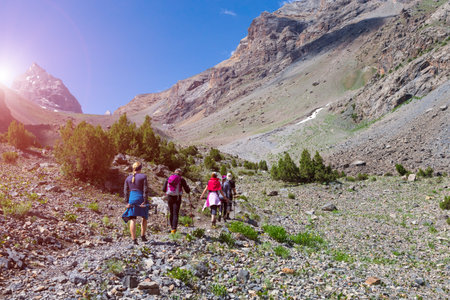 Men and Women going up with Hiking Gear sporty Clothing on bright Mountain Landscape background with...