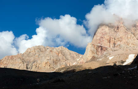 Unusual Color Rocky Walls Orange Red Peaks with Black Silhouette Area on foreground and Blue Sky with Beautiful Clouds on Backgroundの写真素材