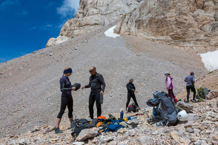 Group of Alpine Climbers Working on setting up Camping Tents with Many Gear Dropped Around and Rocky Mountain Moraine on Backgroundの写真素材