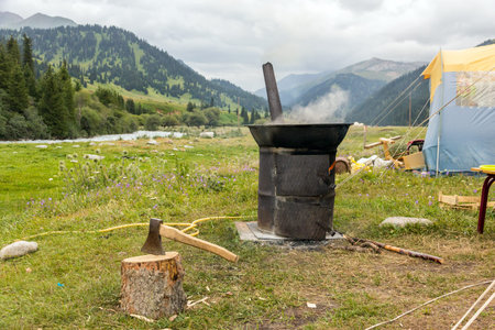 Vintage Style Traditional Iron Stove with Smoking Chimneys Green Meadow and Mountain Stream on Backgroundの写真素材