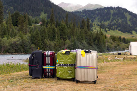 Mountain View with Forest Hills and River Stream and Many Suitcases of different type and colorsの写真素材