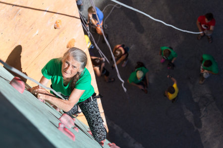 Elderly Female Moving Up on Outdoor Climbing Wall Sporty Clothing on Fitness Training Intense but...