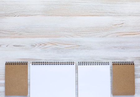 Soft Planked Wooden Board with Line of Notepads Opened and Folded in Warm Serene Color Tone