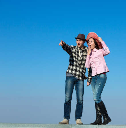 Young Man and Woman Looking Into Far and Expressing Delight and Amazement Casual Holiday Style Clothing Blue Sky Backgroundの写真素材