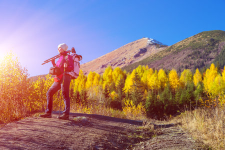 Autumnal Forest and Mountains and Woman Hiker Portrait with Sun Shining and Blue Sky