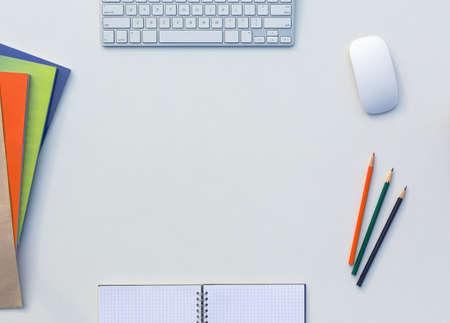 Creative Office White Table with Matching Color Orange Green Blue Magazines and Pencils Computer Keyboard and Mouse Opened Notepad Top Viewの写真素材