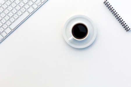 Image of White Office Table with Computer Keyboard Opened Cropped Notepad and Coffee Mug from aboveの写真素材