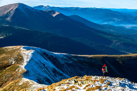 Body of Hiker bright sporty Clothing staying over Mountain Precipice foggy Peaks stacked on distant...