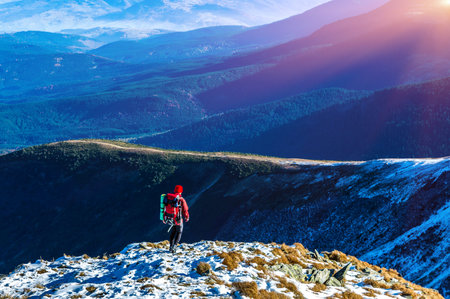 Walking Hiker in Red Jacket with Backpack on Snow Slope distant Mountain Ridges stacked on...
