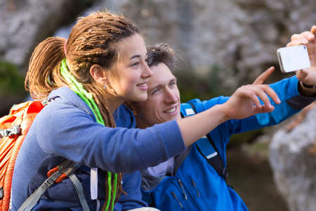 Two Hikers Man and Girl with Dreadlocks Hair Style smiling taking self Portrait Photo with Camera of smart phone on Hike in Spring Time Forestの写真素材