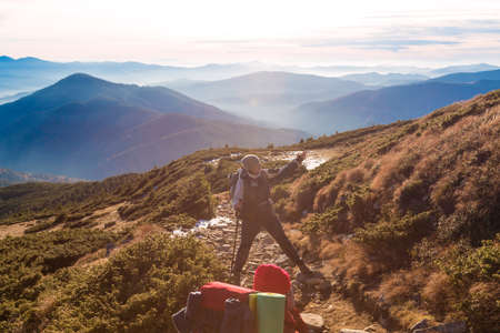 Two Hikers on Trail in Mountains Woman enjoying scenic View stacked foggy Ridges and Peaks on Background Sun shiningの写真素材