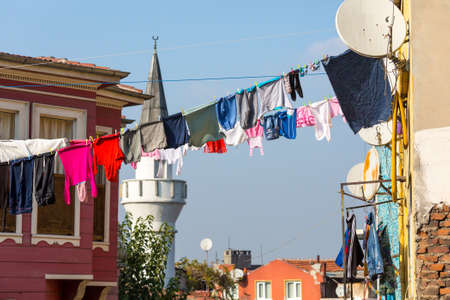 Many Clothing hanging on Clothesline across Street of old City Tower Minaret of Mosque on Backgroundの写真素材