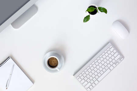 Modern trendy Working Place of Designer with large Computer Monitor Keyboard Notepad Pen and Mouse on White Desk with green Flower and Coffee Mugの写真素材