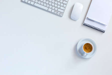 Morning Business Background with cropped Computer Keyboard and Mouse blank Paper Notepad and Pen Coffee Mug with pleasant colorful Cappuccino all in soft white tonesの写真素材