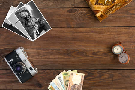 Travel Memories Vintage Composition with old Camera exotic Countries Currency Notes handmade Travel Book Watches with Calendar and Black and White Photos on Hardwood Backgroundの写真素材