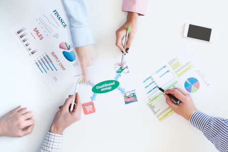 Group of Business People discussing new Product Strategy top View Business Meeting with Paper Charts on White Desk Hands pointing with pensの写真素材