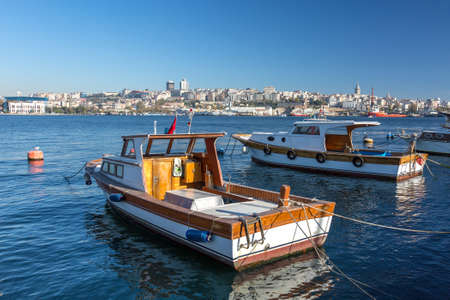 Two wooden white and orange Motor Boats at Pier located on River or Sea Harbor with city View on Background outdoors sunny Dayの写真素材