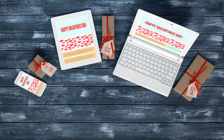 Working Place of web Designer on Valentines Day on dark Wood Table with responsive Site Theme on Laptop Tablet and Telephone Screens and wrapped Gift Boxes with Tags Top View flat Layの写真素材