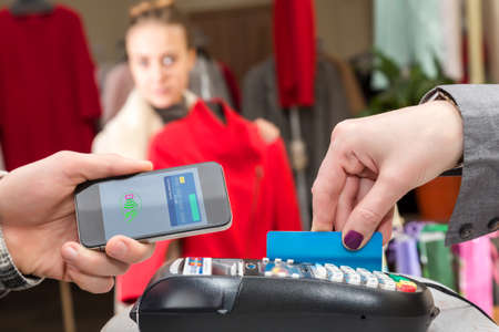 Near Field Communication - Man completing mobile Payment Woman shoppingの写真素材