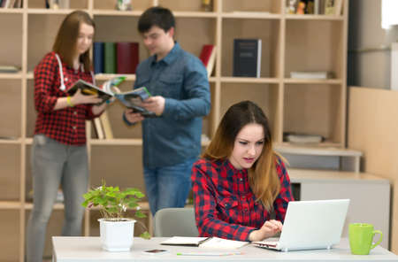 Young Woman working at Laptop other people interacting on Backgroundの写真素材