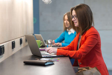 Two young Women working on Computers at wooden Bar Counterの写真素材