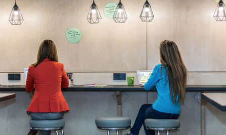 Two Women working on Computers at wooden Wall Tableの写真素材