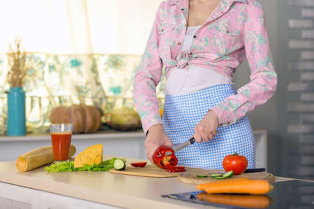Body and Hands of Woman cutting Vegetables in domestic Kitchenの写真素材