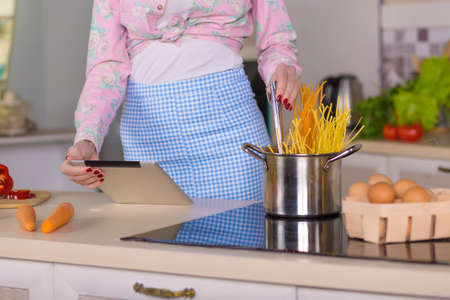 Hands and Body of Woman cooking Pasta reading Recipeの写真素材