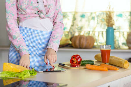 Woman cooking Salad using Recipe on screen of Tabletの写真素材