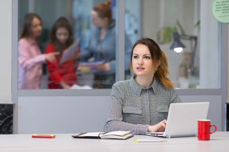 Young female Trainee working on Laptop in Office Interiorの写真素材
