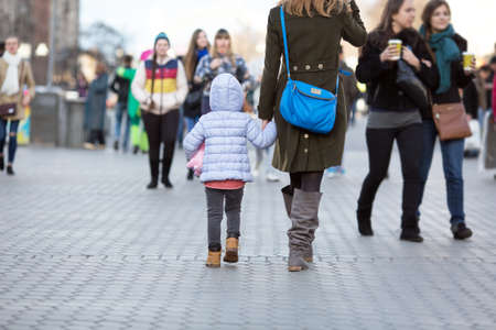 Mother and Daughter walking on City Street among Crowdの写真素材
