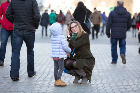 Mother and Daughter walking on City Street among Crowdの写真素材