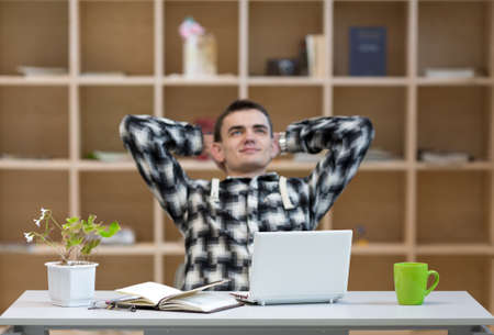 Young Man thinking in relaxed Posture at working Placeの写真素材