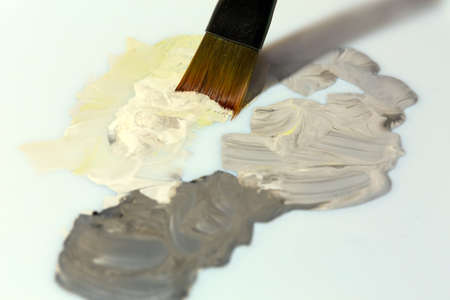 Close up of Brush mixing colors Paints on white Paletteの写真素材