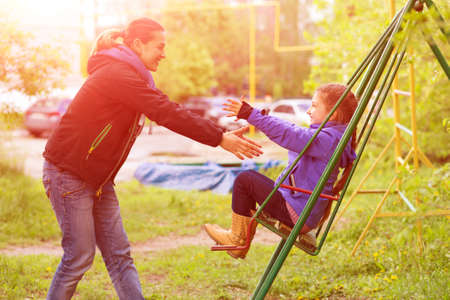 Young Mother Riding Little Daughter on Seesaw in Spring Parkの写真素材