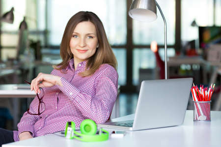 Smiling Business Lady in casual clothing sitting at Office Tableの写真素材