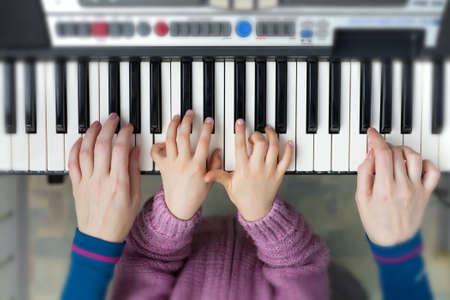 Piano Keyboard top View and Hands of Child and Motherの写真素材