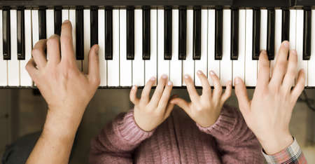 Piano Keyboard top View and Hands of Child Mother and Fatherの写真素材