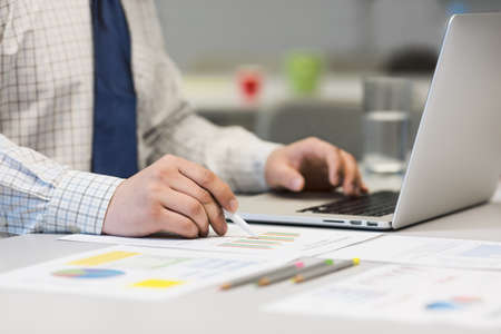 Business man working on a laptop and printed chartsの写真素材