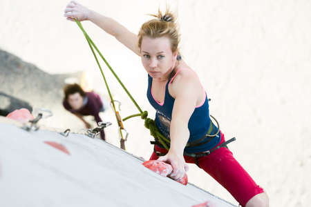 Cute female Athlete hanging on climbing Wall holding Ropeのeditorial素材