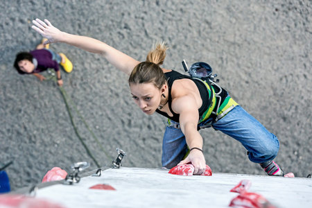Cute female Athlete hanging on climbing Wallの写真素材