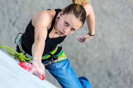 Beautiful female Climber moving up on vertical climbing Wall