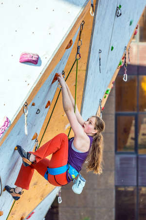 Junior female Athlete makes hard move on climbing Wallのeditorial素材